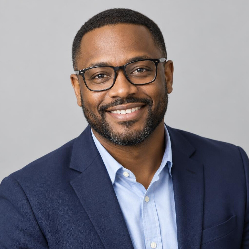 Black man in glasses smiling in studio portrait